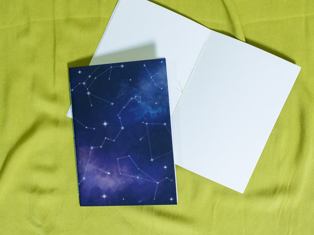 Sketchbook with star constellation design on a green fabric background