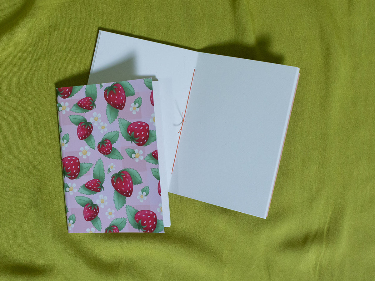 Small sketchbook with strawberry pattern on a green fabric background