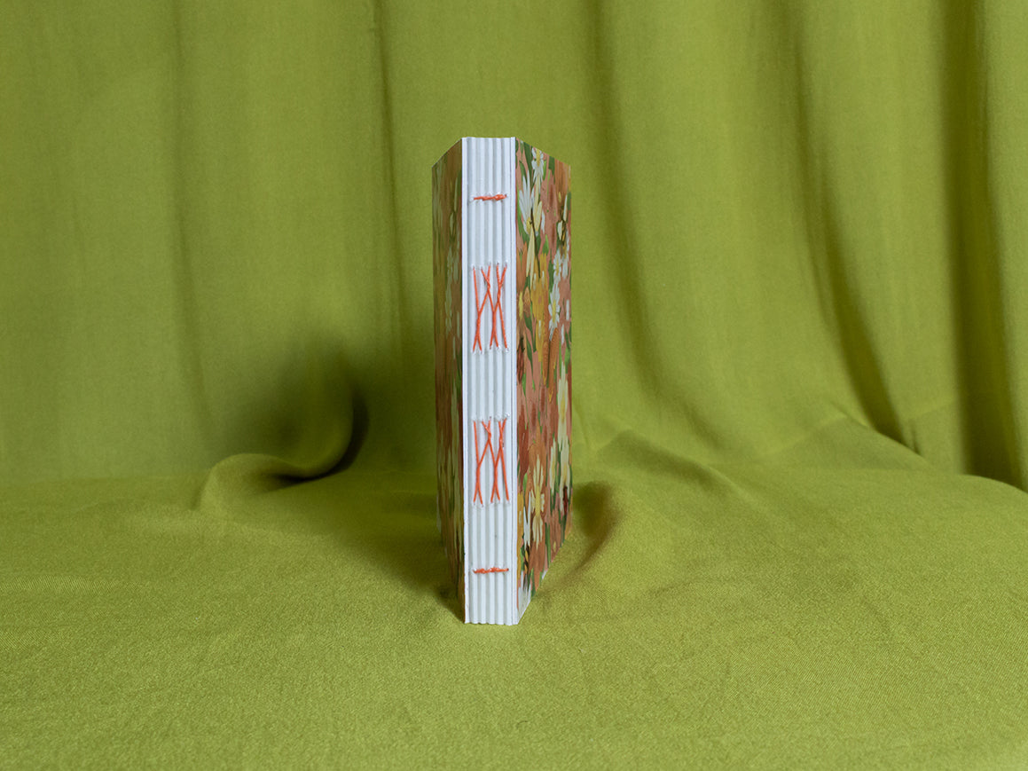 Open spine sketchbook with floral design on a green fabric background