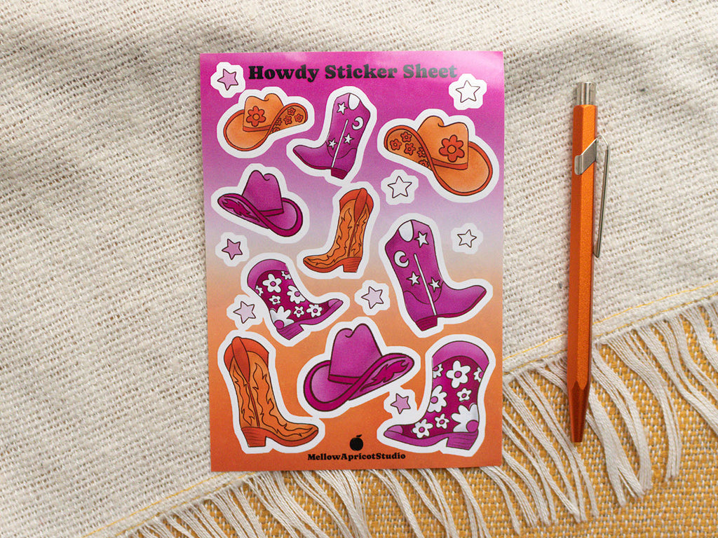 Sheet of howdy-themed stickers with cowboy hats and boots on a textured fabric background.