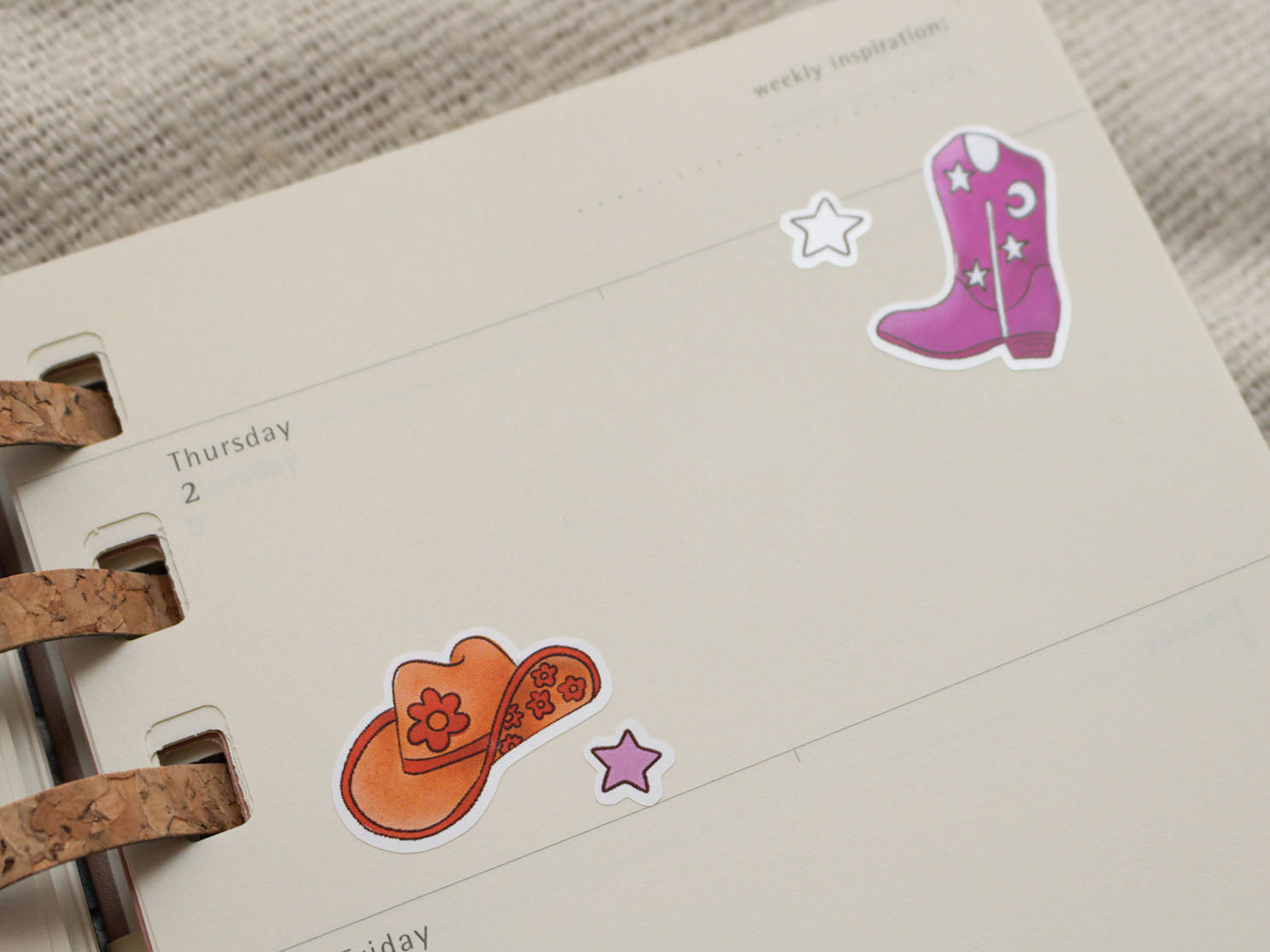 Stickers of a cowboy hat and purple boot on a planner page.