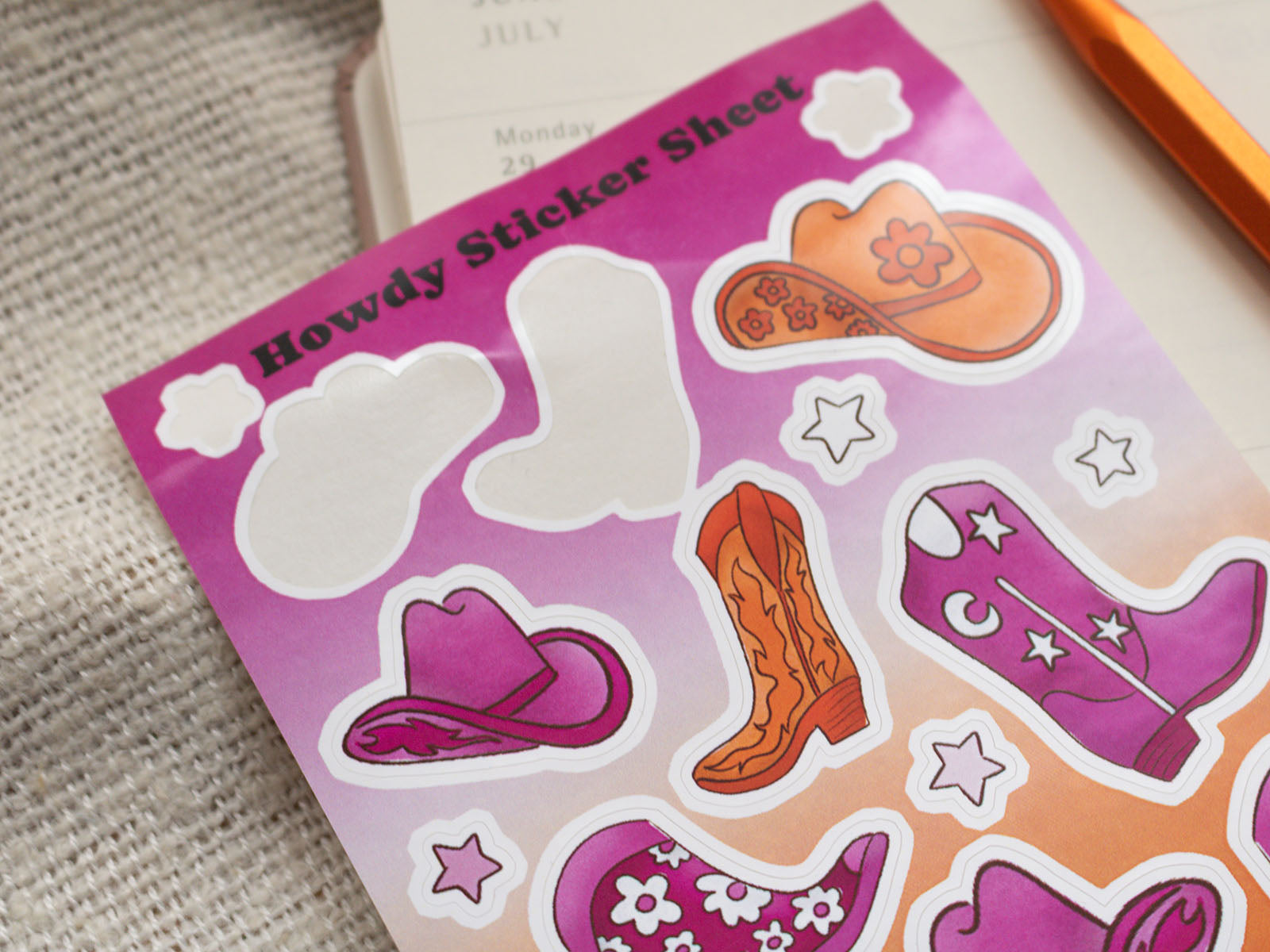 Pink sticker sheet with cowboy-themed stickers on a textured surface