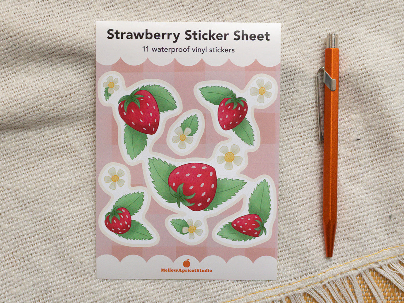 Strawberry sticker sheet with 11 waterproof vinyl stickers on a textured surface with a pen.