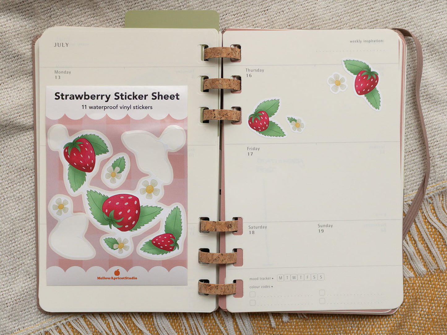 Open planner with strawberry sticker sheet on a textured surface