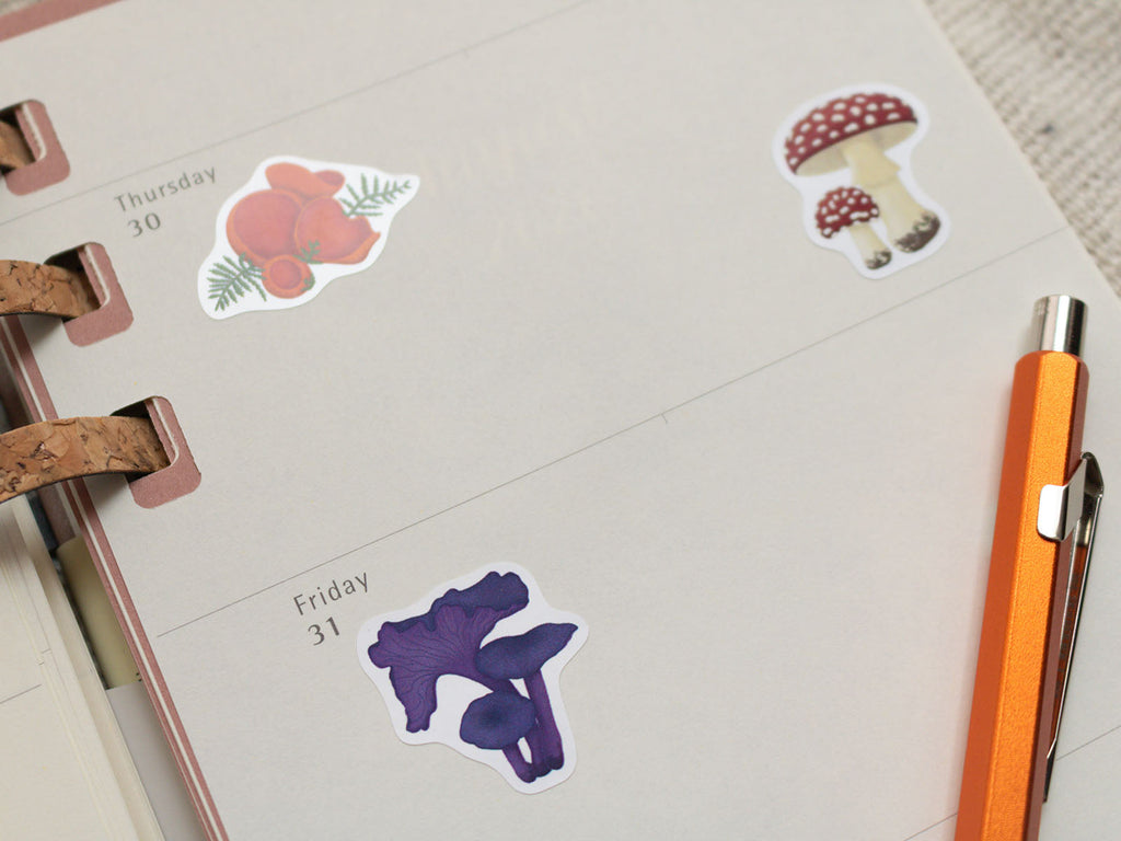 Mushroom stickers on a planner with a pen next to it