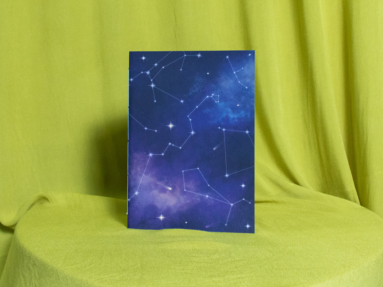 Sketchbook with star constellation design on a green fabric background