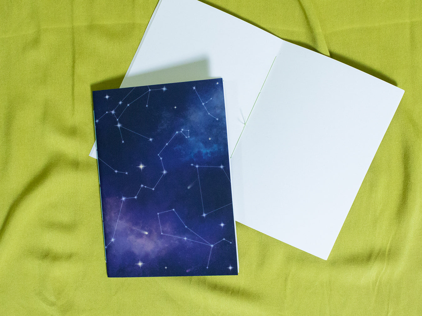 Sketchbook with star constellation design on a green fabric background