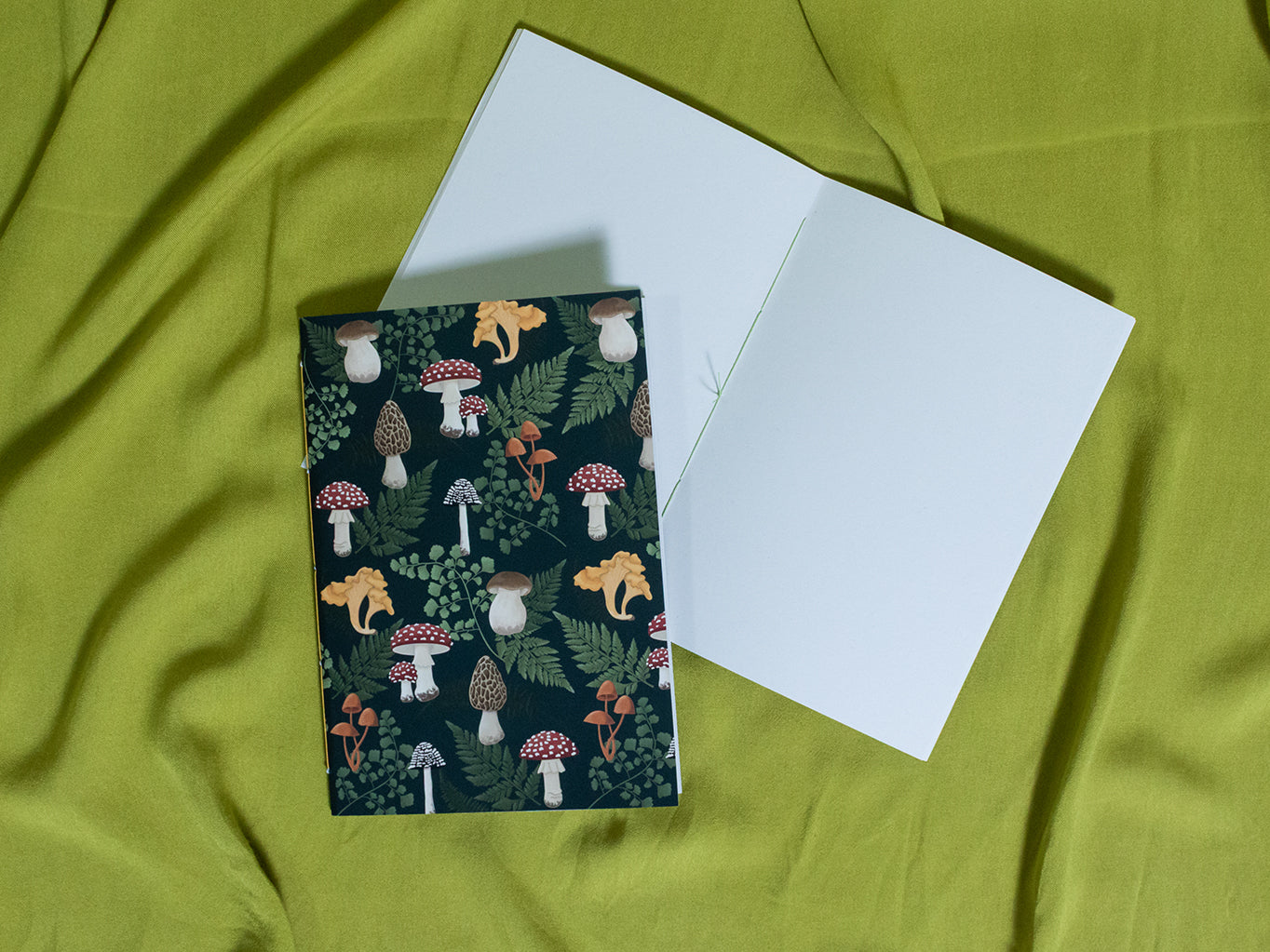 Sketchbook with mushroom pattern on a green fabric background