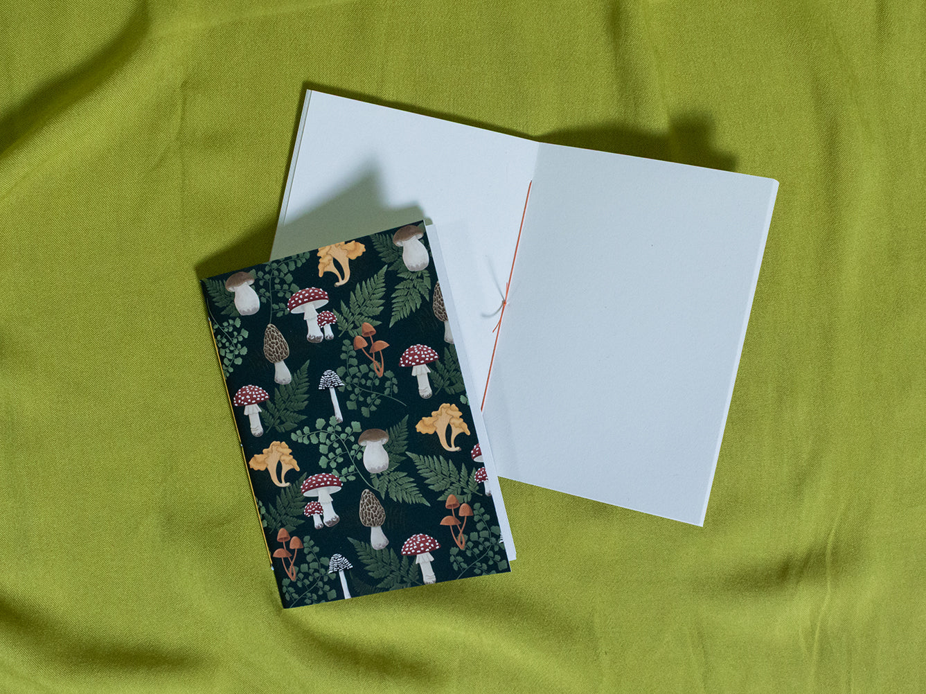 Sketchbook with a mushroom pattern cover on a green fabric background