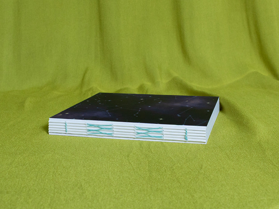 Square sketchbook with a cosmic cover on a green fabric background