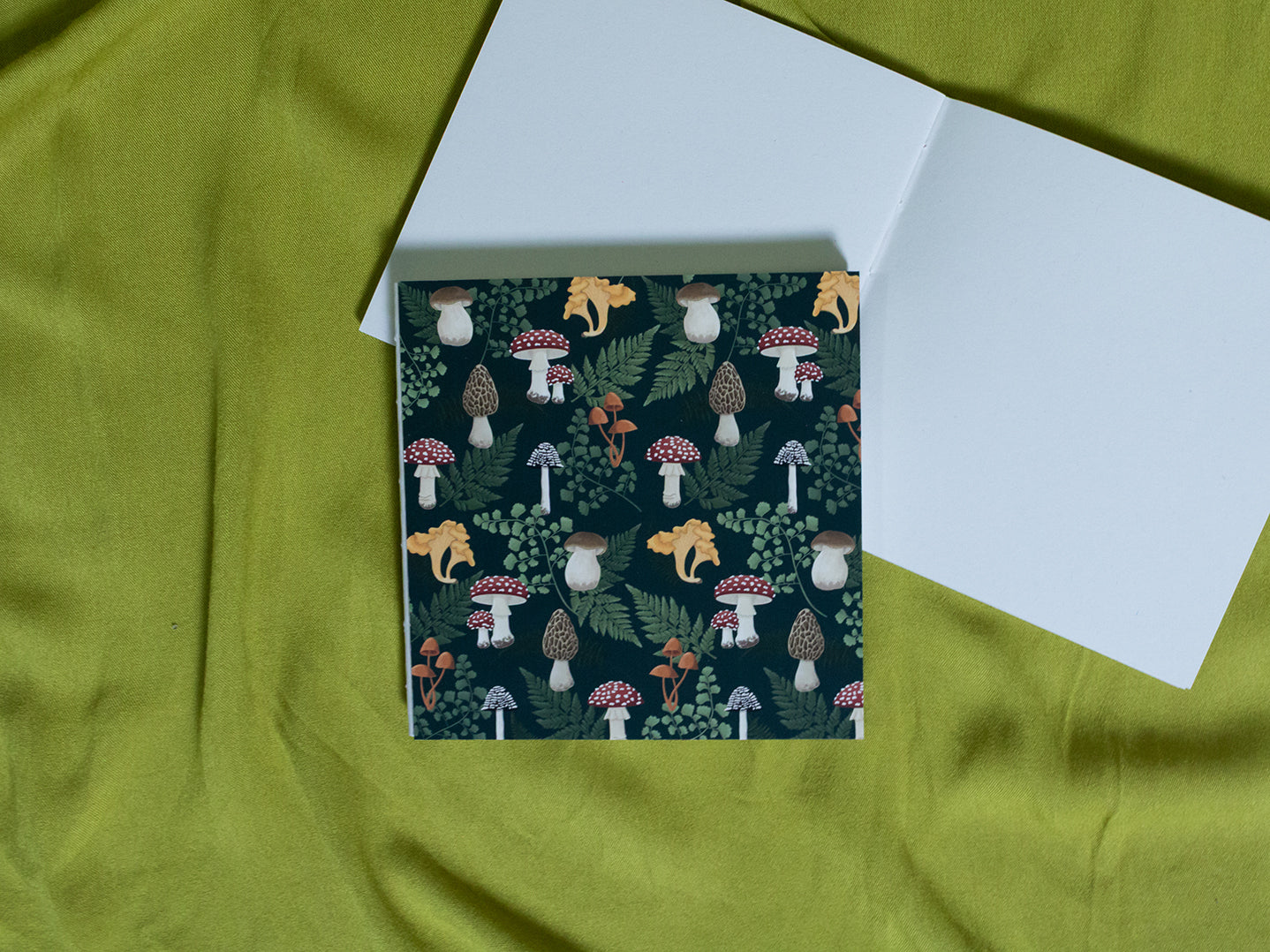 Square sketchbook with forest design featuring mushrooms on a green fabric background